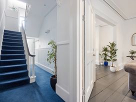 A hallway with blue carpeted stairs and plants near doorways at 8 Richmond Road in Exeter
