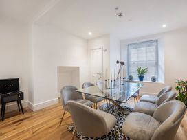 A dining room with a glass table surrounded by six chairs and a record player on a stand at 8 Richmond Road in Exeter