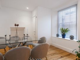 A dining room with a glass table surrounded by gray chairs and a window with blinds and plants at 8 Richmond Road in Exeter