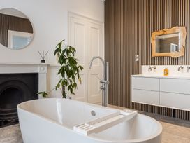 A bathroom with a freestanding bathtub a plant a round mirror and a wooden framed mirror at 8 Richmond Road in Exeter