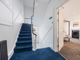 A staircase with blue carpet leading to a landing that connects to a bedroom with a fireplace at 8 Richmond Road in Exeter