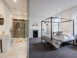 A bedroom with a canopy bed next to a bathroom with a shower and sink at 8 Richmond Road in Exeter