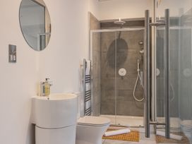 A bathroom with a toilet sink round mirror towel rack and a glass enclosed shower at 8 Richmond Road in Exeter