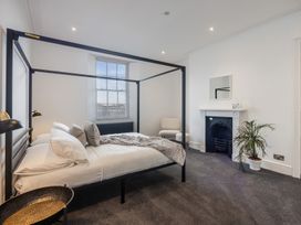 A bedroom with a canopy bed a window a chair a fireplace and a potted plant at 8 Richmond Road in Exeter