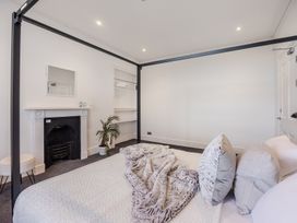 A bedroom with a four-poster bed a fireplace a small plant and an open closet at 8 Richmond Road in Exeter