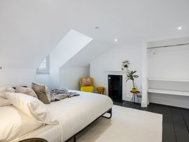 A bedroom with a bed pillows and blankets a yellow chair a small stool a fireplace plants and an open closet at 8 Richmond Road in Exeter