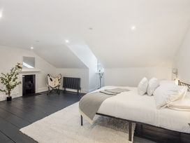 A bedroom with a bed on a rug a chair a fireplace and a plant at 8 Richmond Road in Exeter