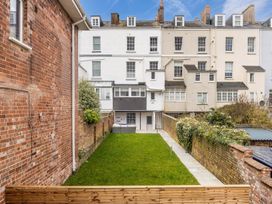 A garden with grass and paved path between two brick walls behind a residential building at 8 Richmond Road in Exeter
