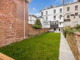 A garden with green grass and a stone pathway between brick walls at 8 Richmond Road in Exeter