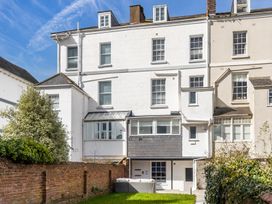 The back of a multi storey white building with a small garden area and outdoor seating at 8 Richmond Road in Exeter