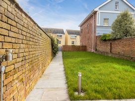 A paved walkway next to a brick wall and a grass lawn beside a house at 8 Richmond Road in Exeter