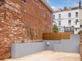 A small outdoor concrete area with grey walls and wooden fencing next to a brick building at 8 Richmond Road in Exeter