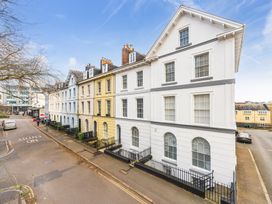 A street with a row of multi-story terrace houses with white blue and yellow facades at 8 Richmond Road in Exeter