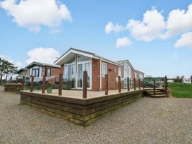 A wooden lodge with decking and steps at Gentle Tide in Hasguard Cross near Little Haven
