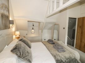 A bedroom with a bed and a shelf at Cotstone Cottage in Chipping Campden