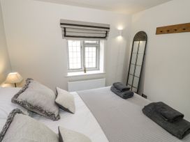 A bedroom with a bed, towels on top and a window at Cotstone Cottage, Chipping Campden