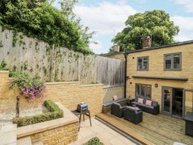 A garden with decking, furniture and a grill at Cotstone Cottage in Chipping Campden