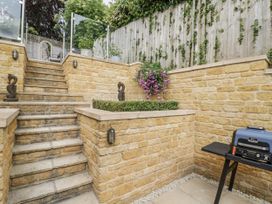 A garden with stone walls, stairs, flowers in a planter, and a barbecue at Cotstone Cottage Chipping Campden