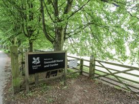 A sign for Snowshill Manor and Garden with trees and a path at Snowshill Manor in Chipping Campden