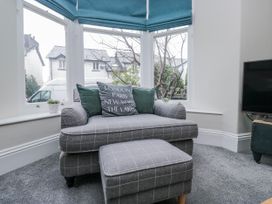 A living room with an armchair and ottoman at The Thistles Bowness-On-Windermere