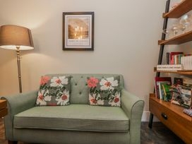 A living room with a sofa and bookshelves at The Thistles in Bowness-On-Windermere