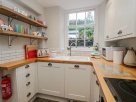 A kitchen with a sink and shelving with cups at The Thistles in Bowness-On-Windermere
