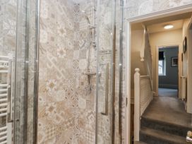 A bathroom with a shower and tiled wall at The Thistles in Bowness-On-Windermere