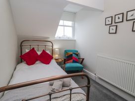 A bedroom with a bed and chair at The Thistles in Bowness-On-Windermere