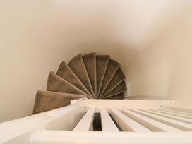 A spiral staircase with brown carpet and white railing near Cirencester