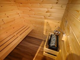 A wooden sauna interior with a bench and a heater with stones at Moel Arthur in Bryniau Clwyd near Denbigh