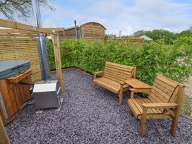An outdoor seating area with wooden benches and a hot tub with a chimney at Moel Arthur in Bryniau Clwyd near Denbigh