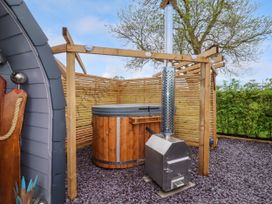 An outdoor wooden hot tub with a metal heater and wooden privacy screen at Moel Arthur in Bryniau Clwyd near Denbigh