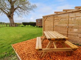 A wooden picnic table on wood chips next to a wooden fence in a grassy backyard at Moel Arthur in Bryniau Clwyd near Denbigh
