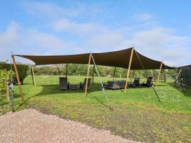An outdoor seating area with a large canopy shade and furniture on grass at Moel Arthur Bryniau Clwyd near Denbigh