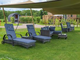 Outdoor seating area with lounge chairs sofas and tables on grass under a canopy at Moel Arthur Bryniau Clwyd near Denbigh