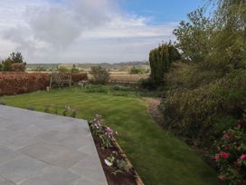 A garden with grass lawn flower bed and tiled patio overlooking countryside at Badachro in Lesbury