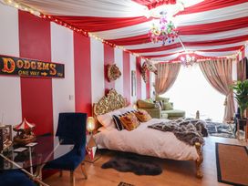 A bedroom with red and white striped walls and ceiling a bed with a gold headboard and pillows and mounted animal heads at Circus Circus in Holywell