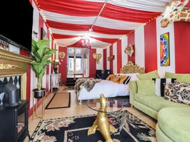 A bedroom with red and white striped walls and ceiling a green sofa a gold ornate bed frame animal head wall decorations and a glass table with a gold base at Circus Circus in Holywell