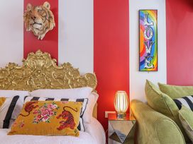 A bedroom with a gold ornate headboard a tiger head wall decoration striped pillows a yellow pillow with tiger designs and a mirrored nightstand with a lamp at Circus Circus in Holywell
