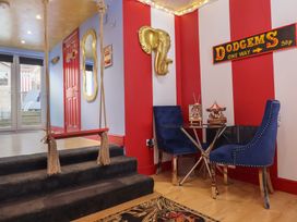 A room with a swing over carpeted stairs and a small glass table with two blue chairs against a red and white striped wall at Circus Circus in Holywell