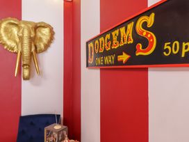 A corner with a golden elephant head wall decoration a blue chair and a sign reading dodgems one way on a red and white striped wall at Circus Circus in Holywell