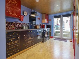 A kitchen with decorated cabinets a washing machine oven and double doors leading outside at Circus Circus in Holywell