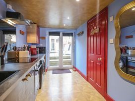 A kitchen with light wood flooring a red door blue walls a countertop with appliances and a glass door leading outside at Circus Circus in Holywell