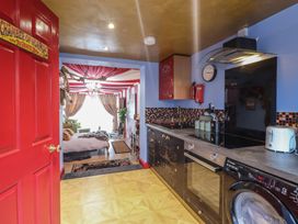 A kitchen with black cabinets and appliances leading to a living area with red and white ceiling drapes at Circus Circus in Holywell