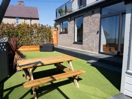 A garden with a wooden table and benches at Seaview House in Llanfairfechan