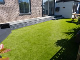 A garden with artificial grass and a patio area at Seaview House in Llanfairfechan