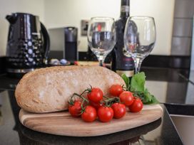 A kitchen counter with bread, tomatoes, basil, wine glasses, and a wine bottle at Jolly Roger Whitby