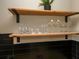 A kitchen shelf with stacked glasses and wine glasses at 5 Thornbarrow Road