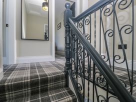 A staircase with a handrail and a mirror in a hallway at 5 Thornbarrow Road