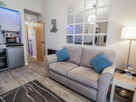 A living room with a sofa and kitchen area at Estuary Escape in Porthmadog